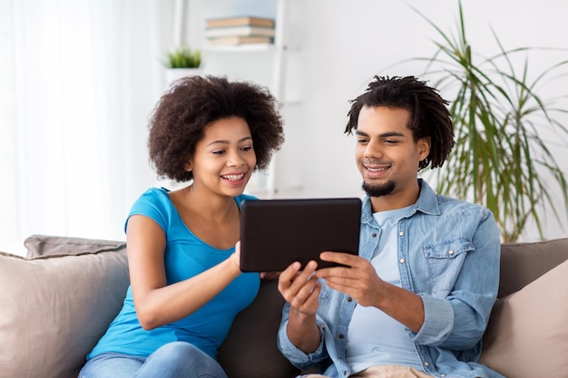 família, tecnologia, internet e conceito de pessoas - casal feliz sorridente com computador tablet pc em casa