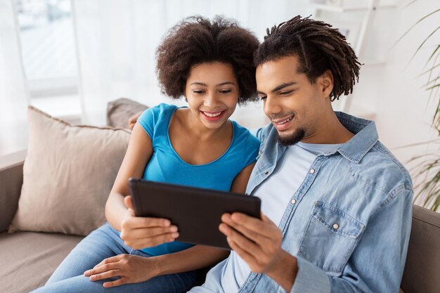 família, tecnologia, internet e conceito de pessoas - casal feliz sorridente com computador tablet pc em casa