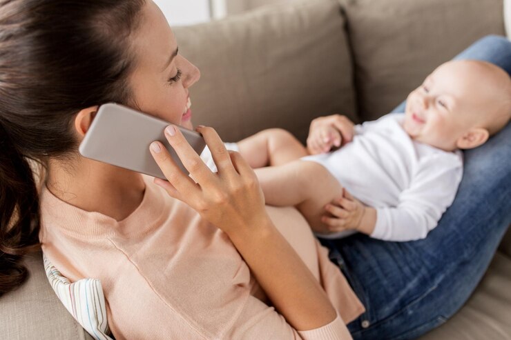 Foto família tecnologia maternidade e pessoas conceito mãe feliz com pequeno bebê menino deitado no sofá e chamando no smartphone em casa