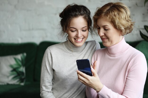 Familia y tecnología Mujer anciana y su hija adulta usando un teléfono inteligente en casa