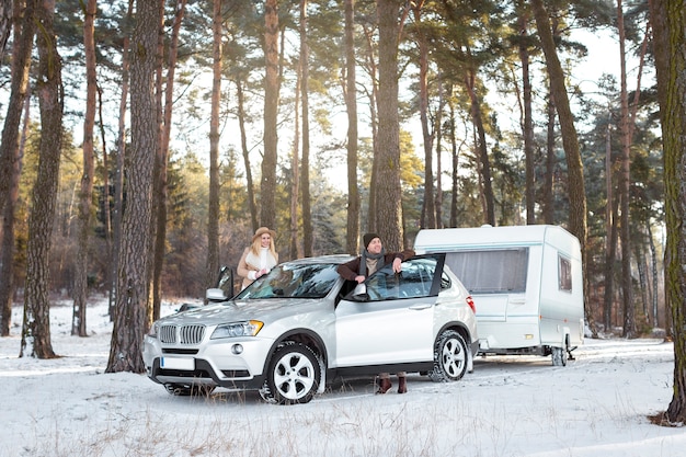 Foto familia de tiro completo con auto al aire libre.