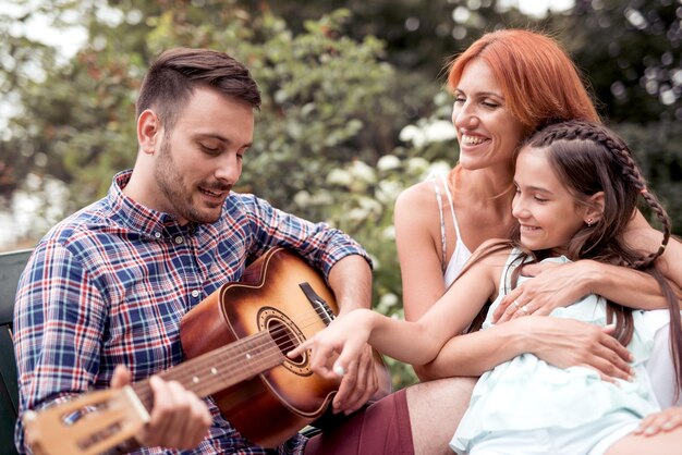 Familia tocando una guitarra juntos en el parque