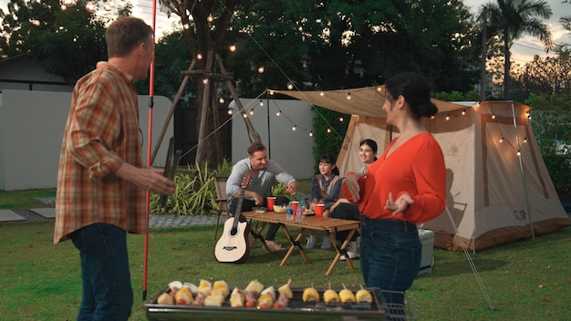 Familia todos juntos acampando en el jardín pareja de ancianos cocinando barbacoa divergencia
