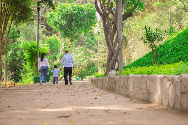 Familia tomados de la mano mientras caminan por un parque durante el día en Perú Lima