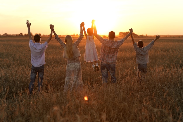 Familia tomados de la mano mirando el atardecer en el campo