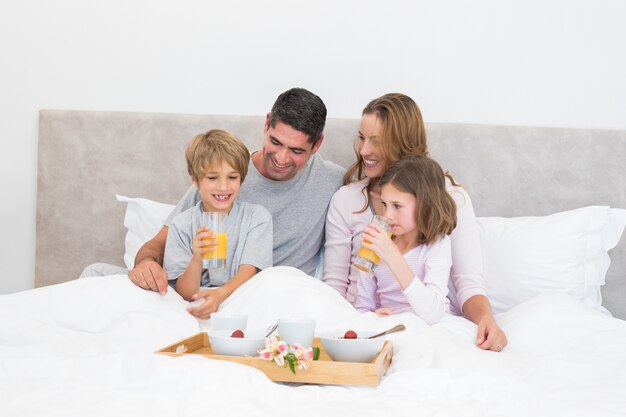 Família tomando café da manhã juntos na cama