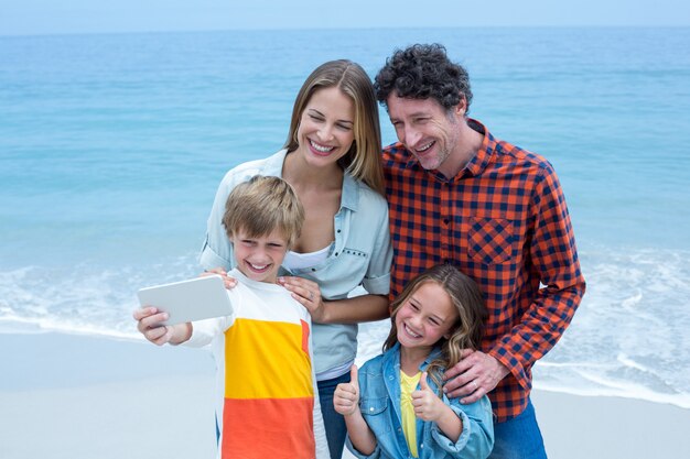 Família tomando selfie em pé na beira-mar