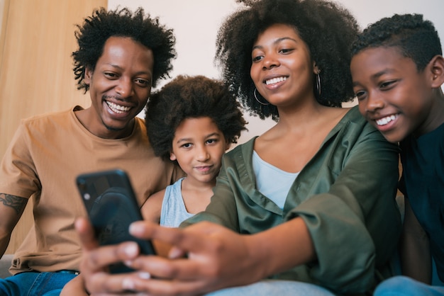 Familia tomando selfie junto con el teléfono en casa.