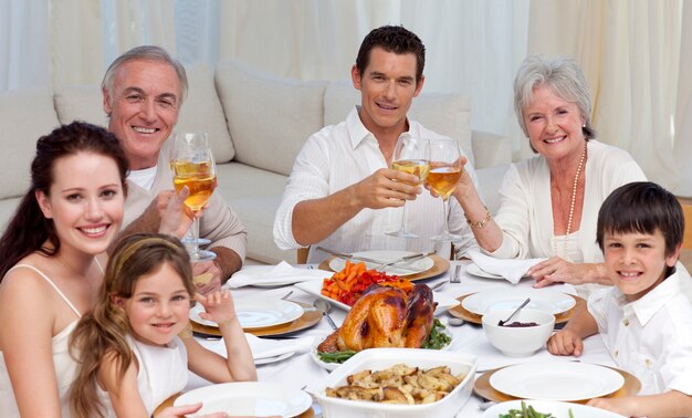 Família torcendo com vinho em um jantar sorrindo para a câmera