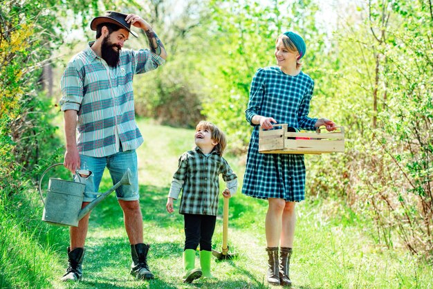 Familia trabajando juntos en la granja Agricultura, jardinería y concepto de familia Familia feliz, madre, padre e hijo, en el fondo del campo de primavera