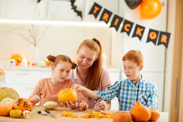 Familia de tres con calabazas en casa