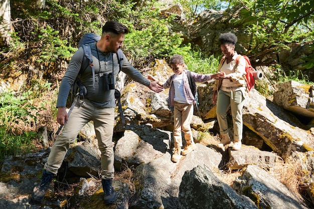 Familia de tres caminando sobre grandes rocas que viajan en la naturaleza salvaje