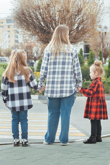 una familia de tres cruzando la calle en un cruce de autos