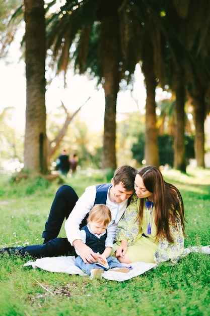 Familia de tres está haciendo un picnic en el parque en un día soleado