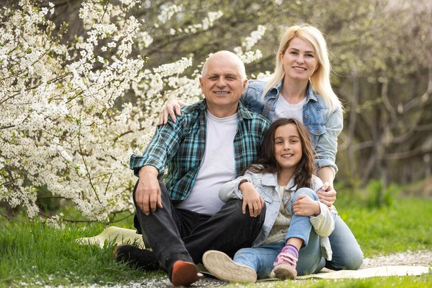 Familia de tres generaciones sentada afuera en la naturaleza primaveral