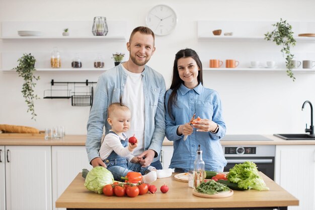 Foto familia de tres haciendo ensalada de verduras para el desayuno