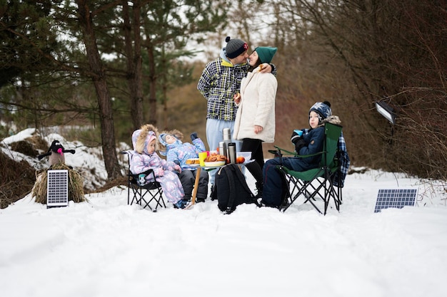 Familia con tres hijos en el bosque de invierno pasando tiempo juntos en un picnic