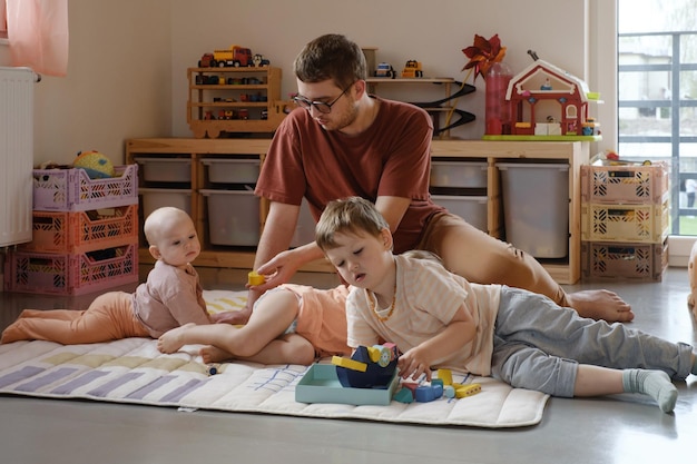 Familia con tres hijos jugando en casa en el suelo