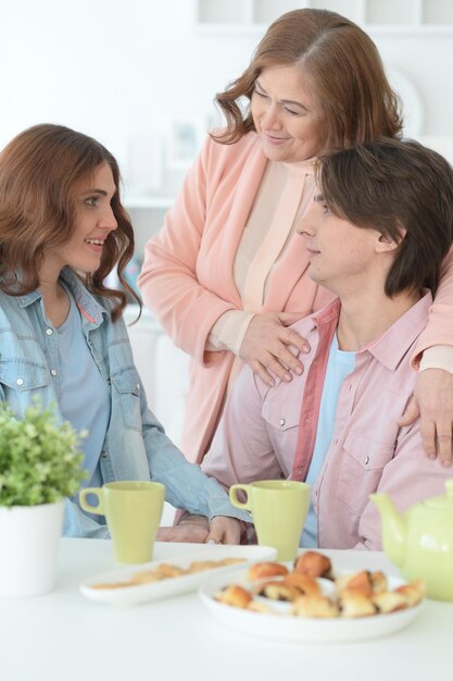 Familia de tres pasando tiempo juntos en la mesa con galletas y té