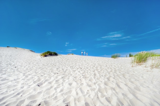 Foto una familia de tres personas camina sobre las dunas de arena cerca de la ciudad de nida, lituania.