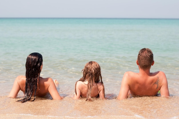 Familia de tres relajándose en la playa