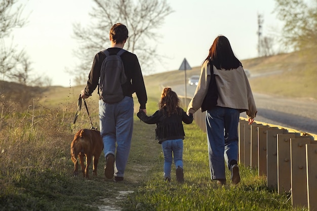 Una familia de tres turistas con un gran perro rojo camina por la carretera