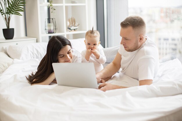 Familia de tres viendo películas a través de la computadora en el dormitorio