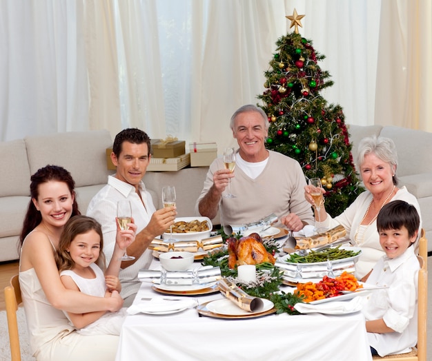 Familia tusting con vino blanco en una cena de Navidad
