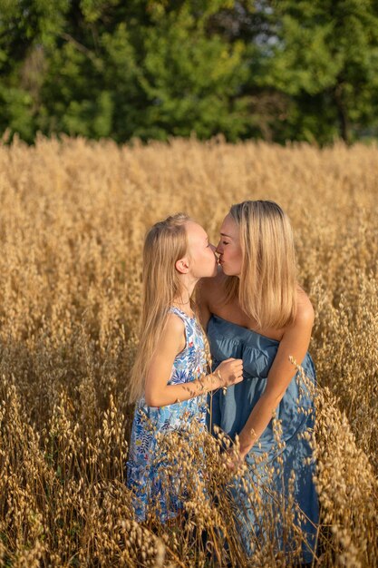 Familia ucraniana una madre amorosa besa a su pequeña hija en un campo de trigo