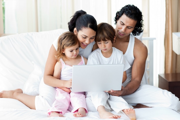 Familia usando una computadora portátil en la cama