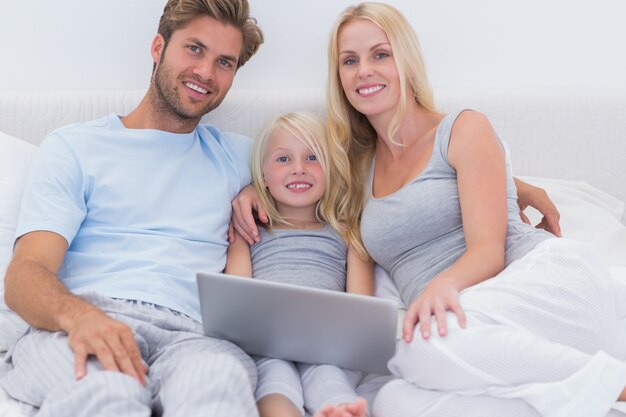 Familia usando una computadora portátil en la cama