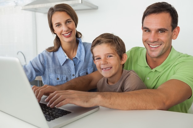 Familia usando una computadora portátil en la cocina