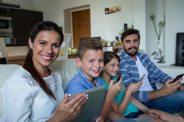 Foto família usando laptop e celular na sala de estar em casa