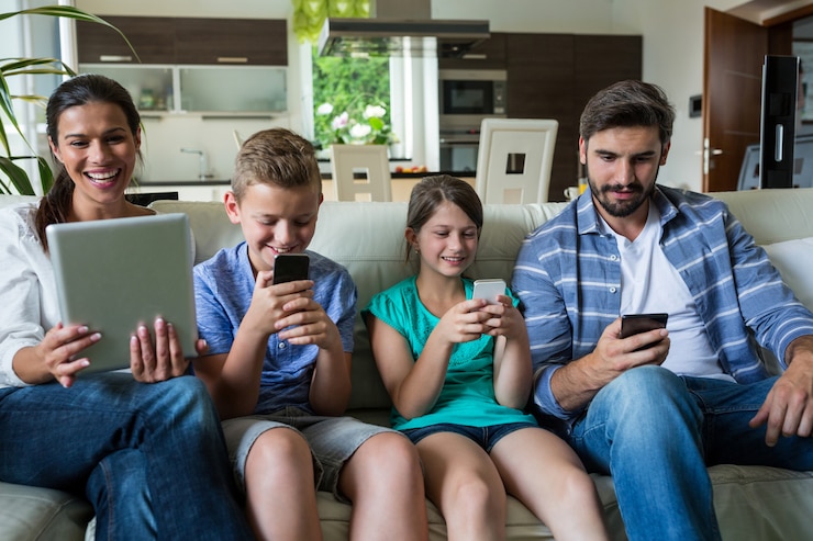 Foto família usando laptop e celular na sala de estar