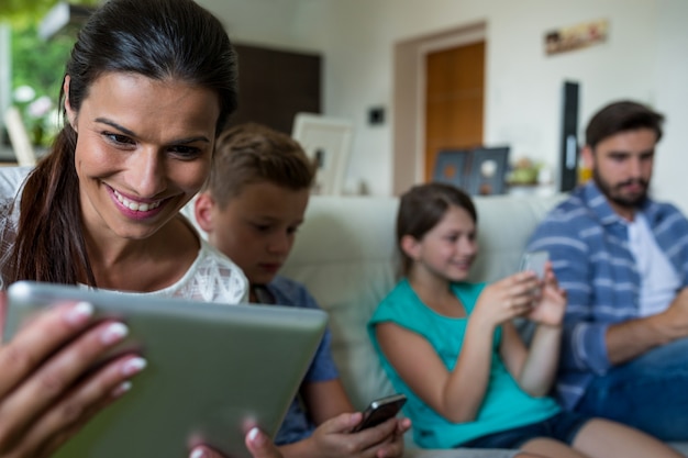 Família usando laptop e celular na sala de estar