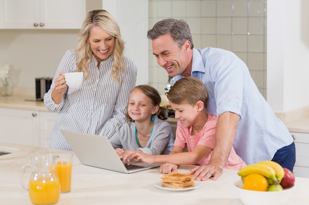 Família usando laptop enquanto tomando café na cozinha