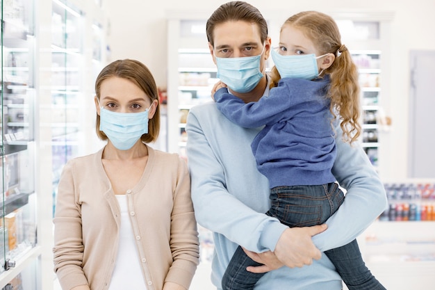 Família usando máscaras protetoras em uma farmácia