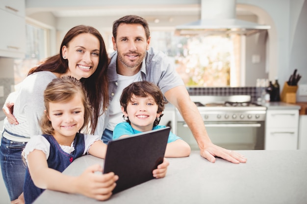 Foto família usando tablet digital em pé na mesa