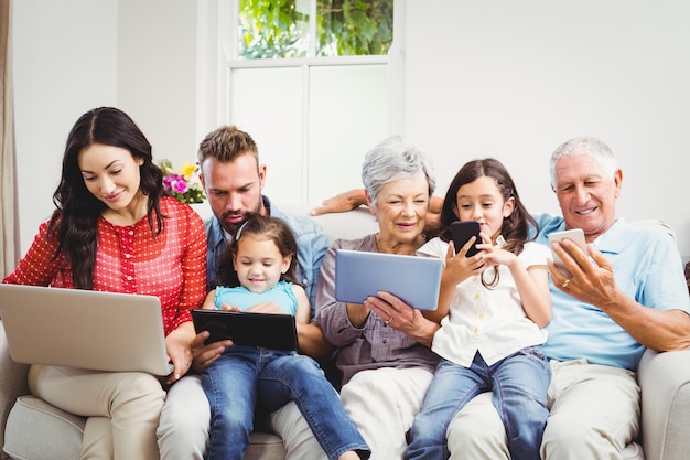 Foto família usando tecnologias enquanto está sentado no sofá