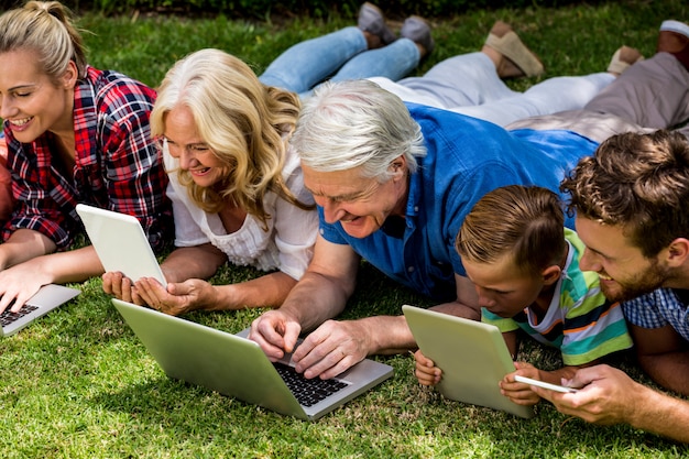 Família usando tecnologias enquanto relaxa no parque