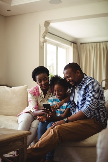 Família usando telefone celular na sala de estar