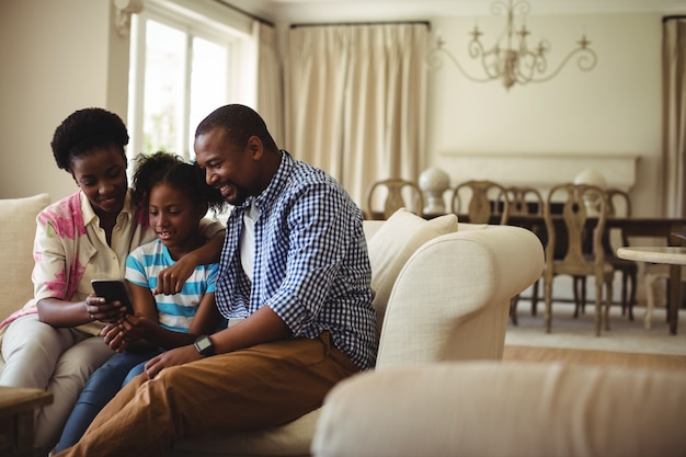 Familia usando el teléfono móvil en la sala de estar