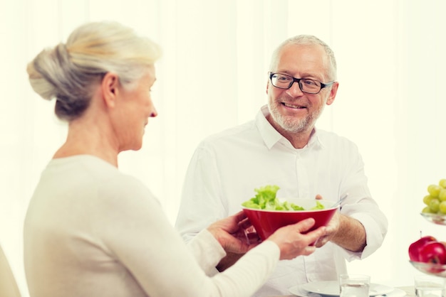 familia, vacaciones, acción de gracias, navidad y concepto de la gente - pareja senior sonriente cenando en casa