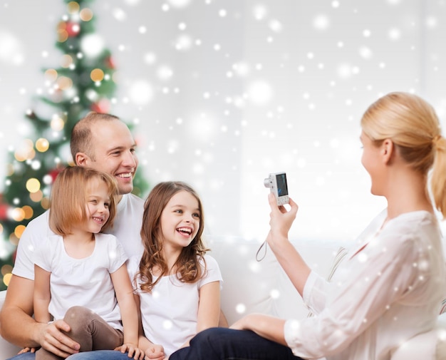 familia, vacaciones, tecnología y gente - madre, padre y niñas sonrientes con cámara fotografiando en casa
