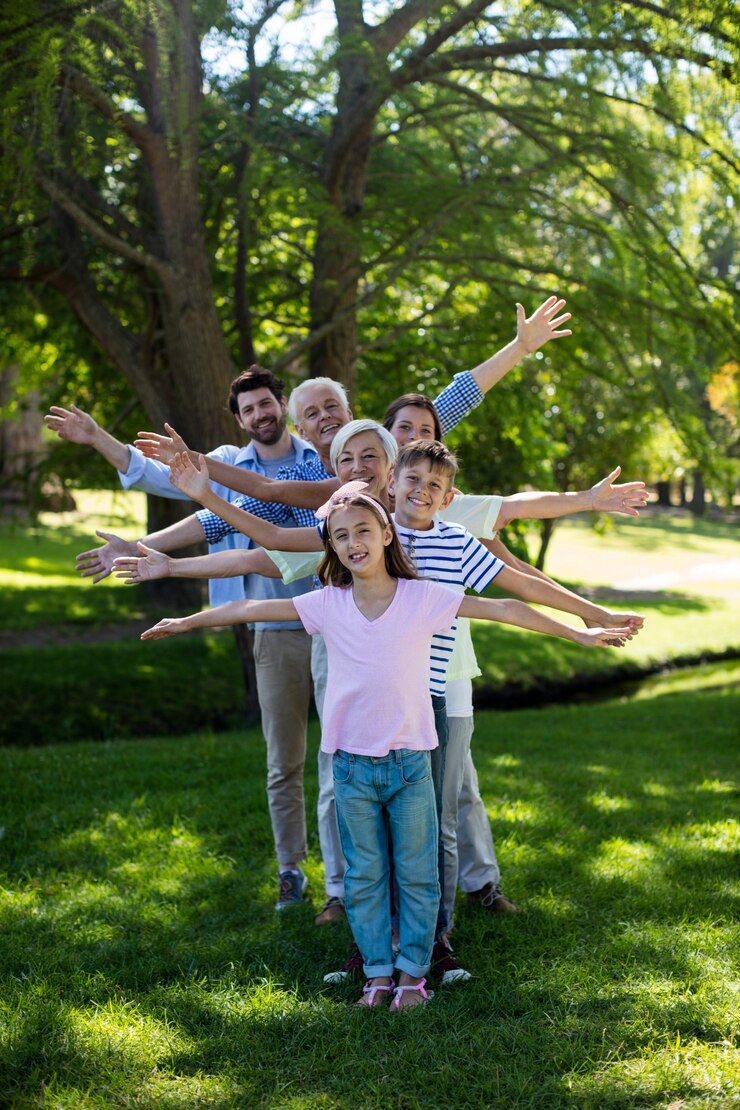 Familia de varias generaciones de pie en fila con los brazos extendidos