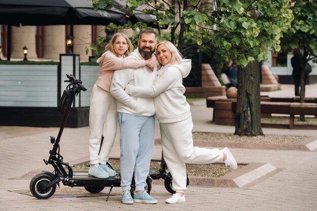 Una familia vestida de blanco se encuentra en la ciudad en patinetes eléctricos.