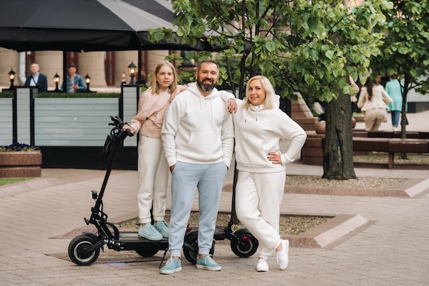 Una familia vestida de blanco se encuentra en la ciudad en patinetes eléctricos.