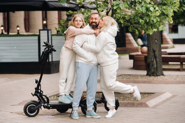 Una familia vestida de blanco se encuentra en la ciudad en patinetes eléctricos.