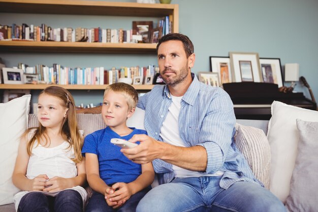 Familia viendo televisión mientras está sentado en el sofá