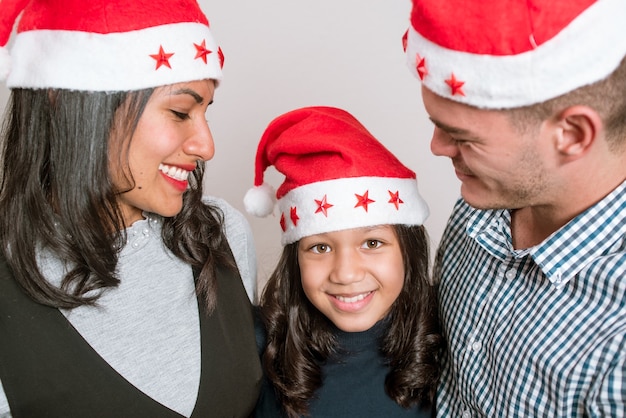 Familia vistiendo jerseys rojos gorras de santa claus